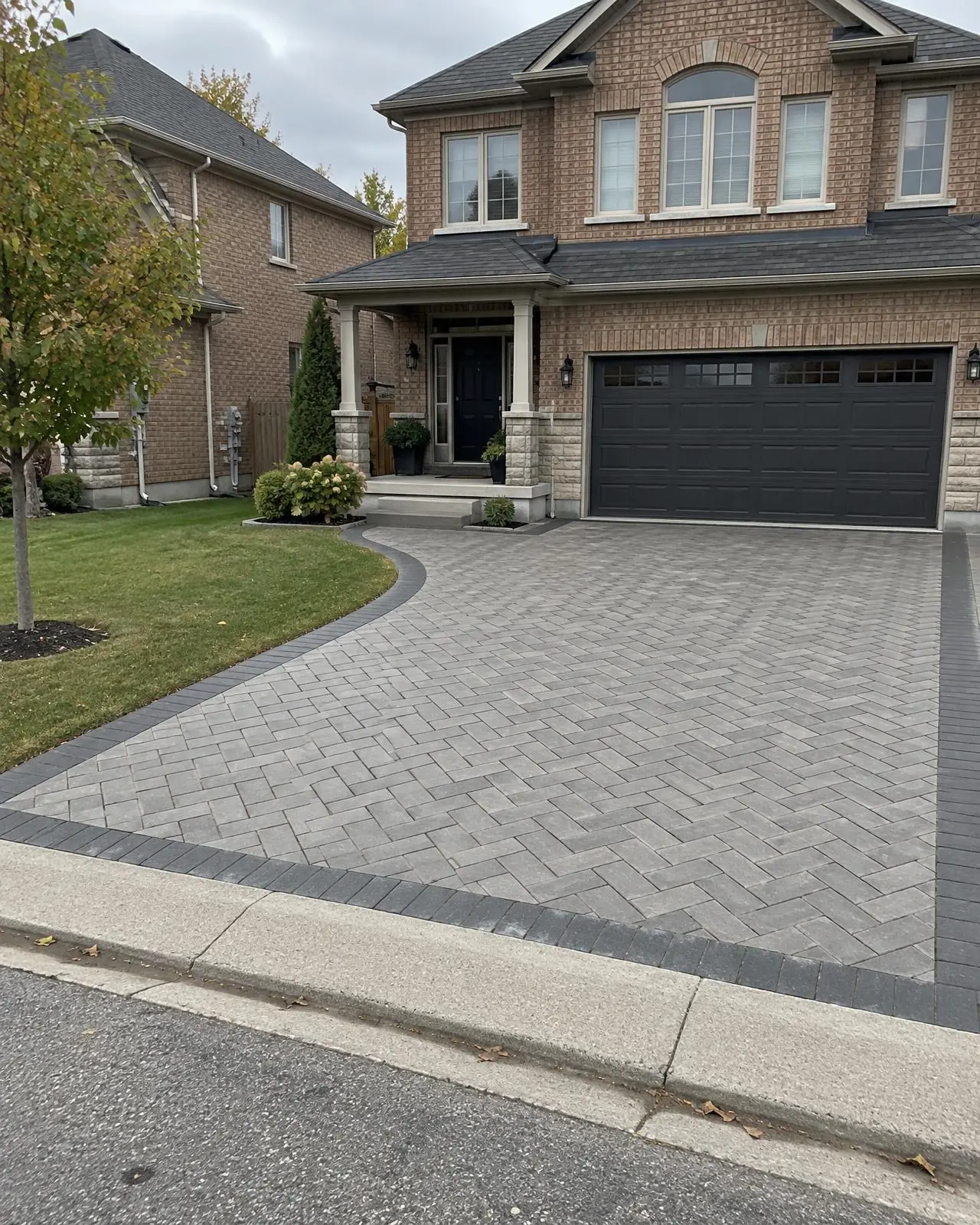 Grey herringbone paver driveway with charcoal border and curved front walkway