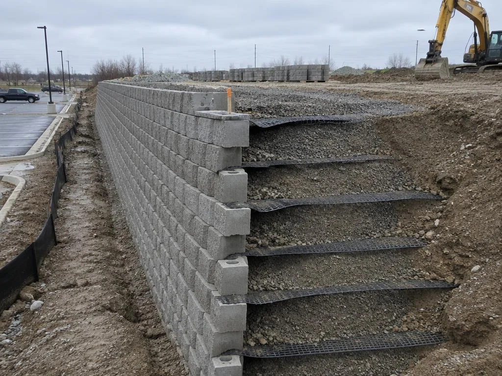 Segmental wall under construction beside a parking lot with geogrid layers visible